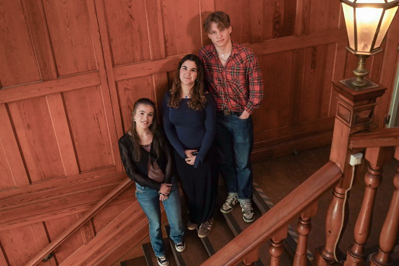 3 elever på Musikkonservatoriet i Falun. 2 tjejer och 1 kille som står i en trappa i entren. En vacker trätrappa i gammal stil.